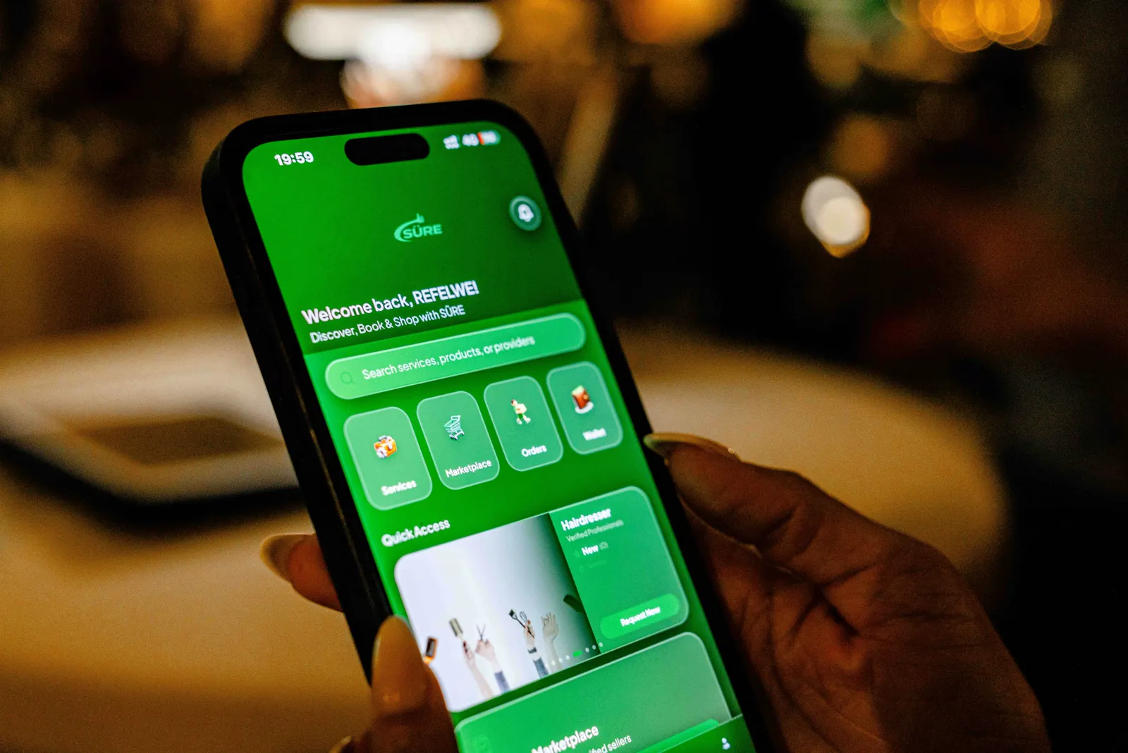 A hand holding a phone showing the SÜRE home screen